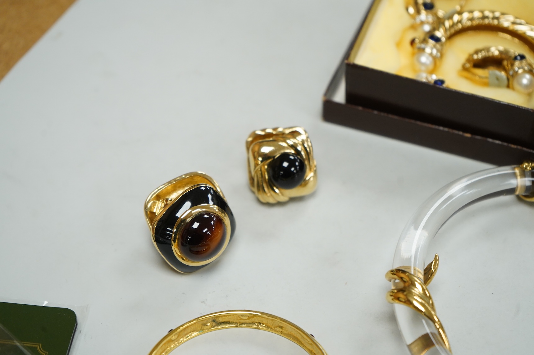 A small group of assorted costume jewellery including a 925 and paste set brooch and pair of ear clips and a gilt metal charm bracelet.